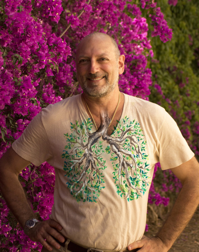 Leslie wearing a lung tree tee shirt in front of a beautiful magenta tree in Barcelona