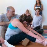 Leslie assisting a student in a forward bend