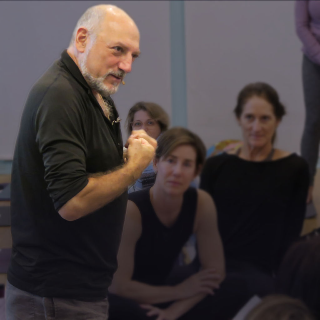 Leslie teaching with students dimly visible behind him.